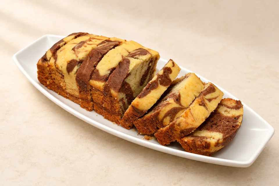 Wide view of a marble loaf with slices fanned across a white platter.
